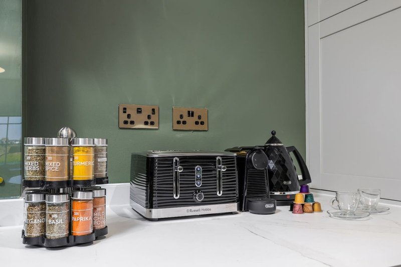 Modern kitchen counter with branded storage jars, black toaster, kettle and electrical outlets