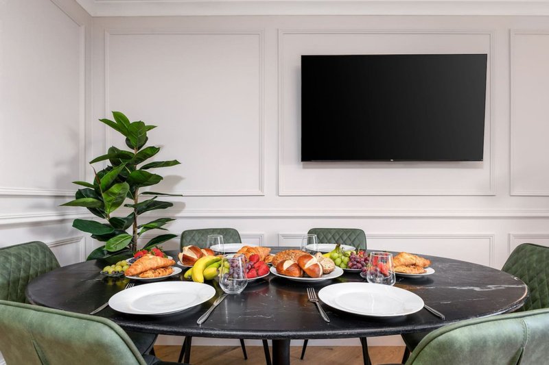 Dining room with round black table, green chairs, place settings and fresh food displays