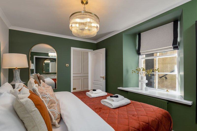 Bedroom with green walls, double bed, mirror, pendant light and window