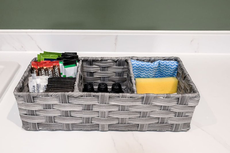 Storage basket with organized linens, cloths, and household items on white shelf