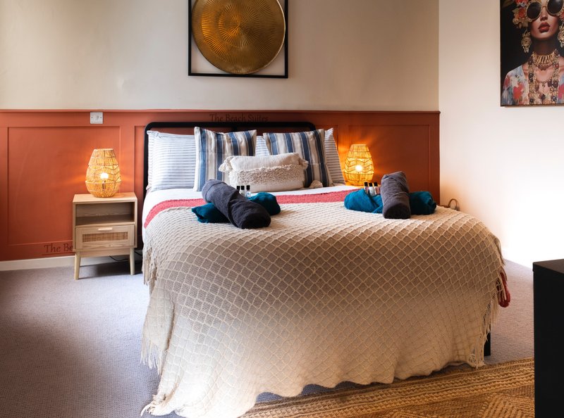 Bedroom with double bed, decorative pillows, bedside lamps, and terracotta accent wall