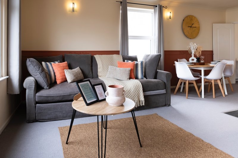 Modern living room with gray sofa, round coffee table, dining area and wall clock