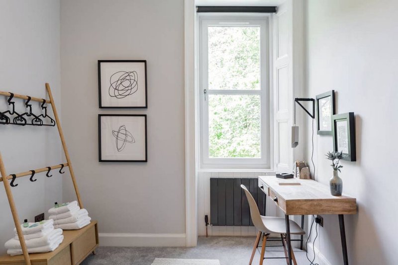 Modern home office with wooden desk, chair, window, and minimalist wall art
