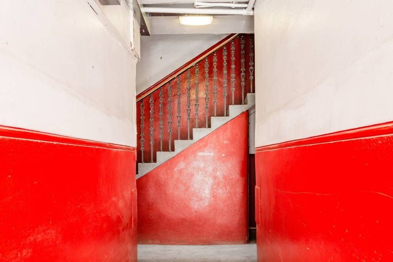Stairwell with red walls, metal banister, and concrete stairs leading upward