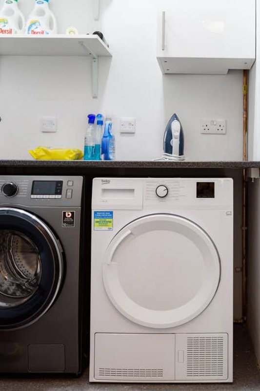 Laundry room with washing machine, tumble dryer, cleaning supplies and countertop storage