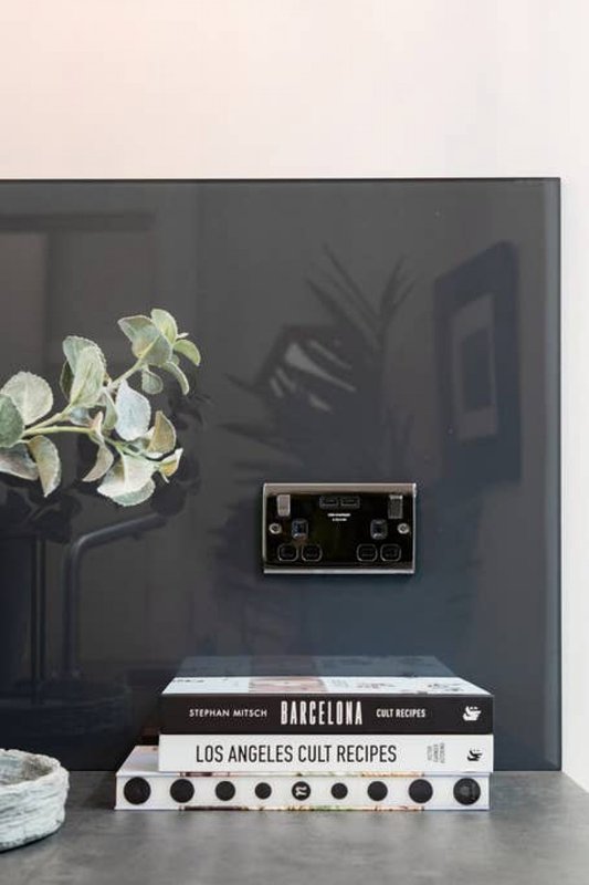 Shelf display with potted plant, stacked books, electrical outlet and decorative items