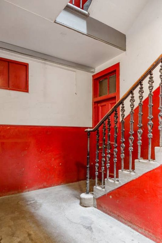 Interior stairwell with red painted walls, metal handrail, and red door at landing