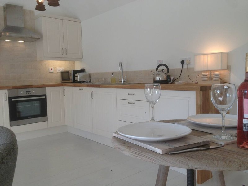 Modern white kitchen with wooden countertop, dining table set with plates and glassware