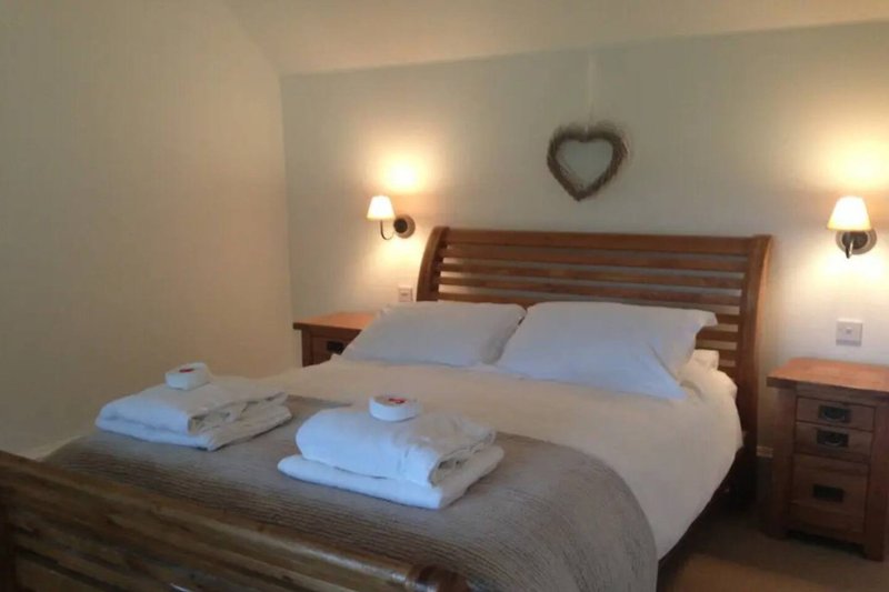 Bedroom with double bed, wooden headboard, bedside lamps, and heart decoration