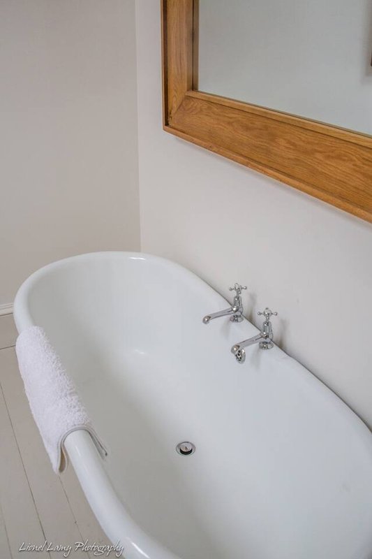 Modern white freestanding bathtub with chrome taps and white towel rail