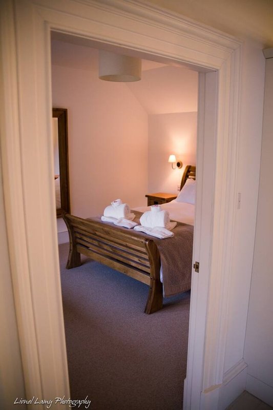 Hotel bedroom viewed through doorway with double bed, wooden frame and bedside lamps