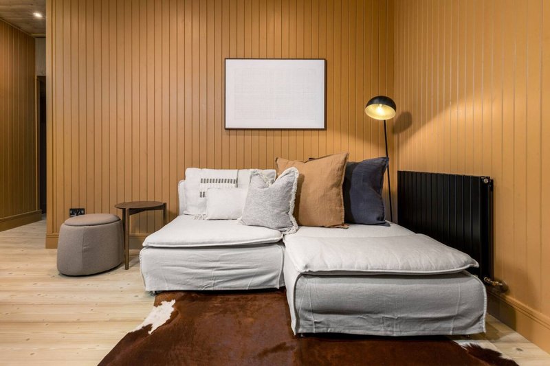 Modern bedroom with two single beds, wooden paneling, floor lamp, and minimalist wall art