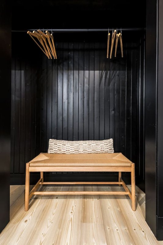 Modern bedroom nook with wooden bench, woven cushion and black corrugated wall backdrop