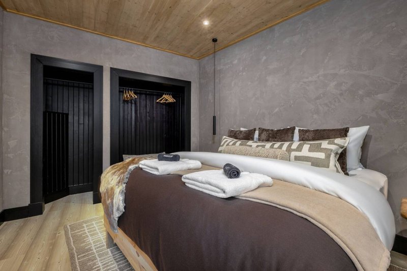 Modern bedroom with double bed, white bedding, brown throw, and black wardrobe doors