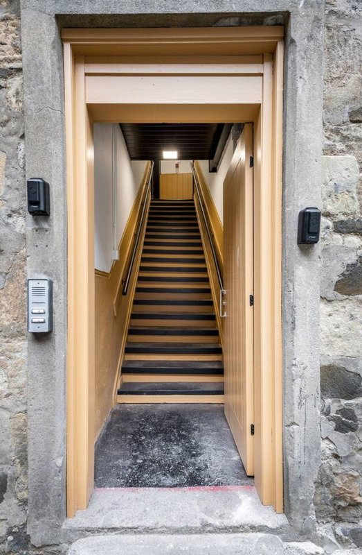 Entrance hallway with wooden staircase leading upward, stone exterior walls, modern lighting fixtures