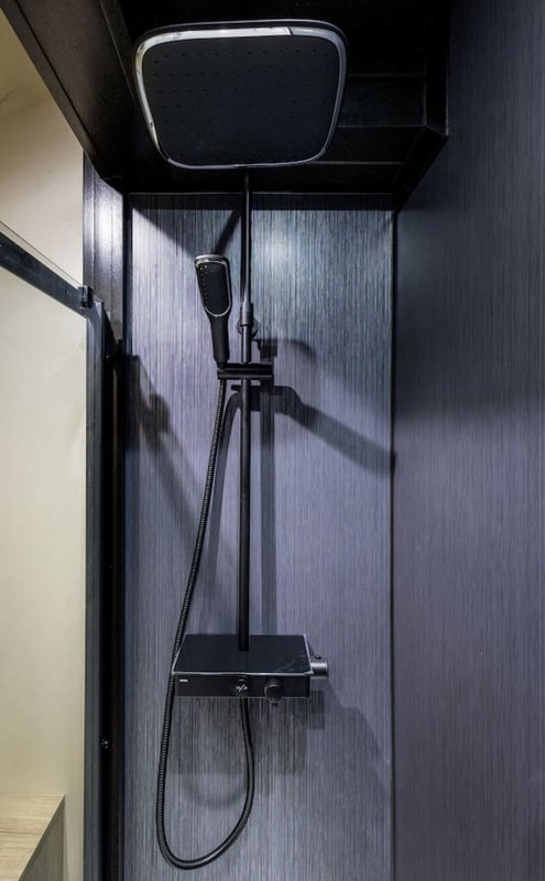 Modern shower enclosure with black fixtures, rainfall showerhead and handheld spray