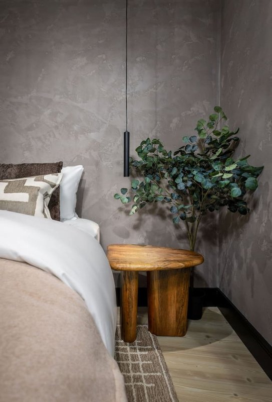 Bedroom corner with bed, wooden side table, potted plant and pendant light