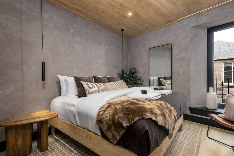 Modern bedroom with double bed, fur throw, wooden ceiling and grey walls