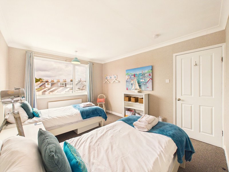 Bright bedroom with two single beds, blue cushions, large window overlooking outdoor stairs, and storage shelving