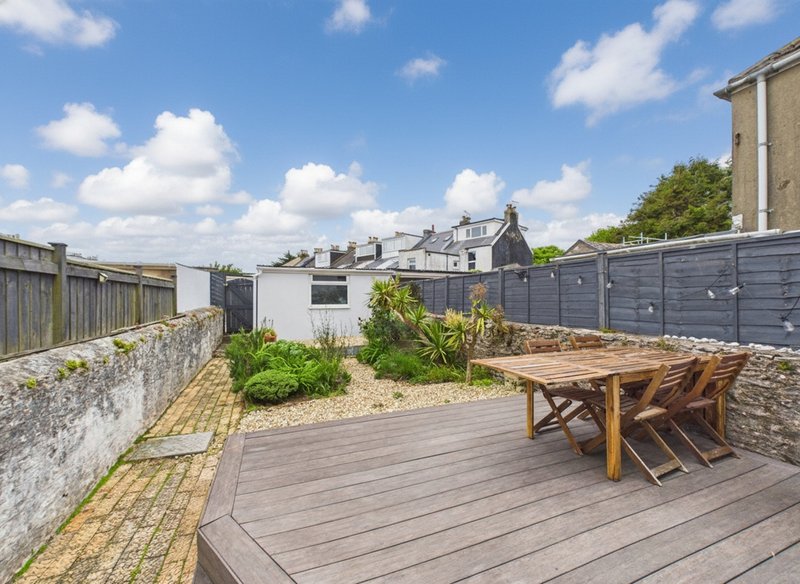 Rooftop terrace with wooden decking, dining table, chairs, and garden beds
