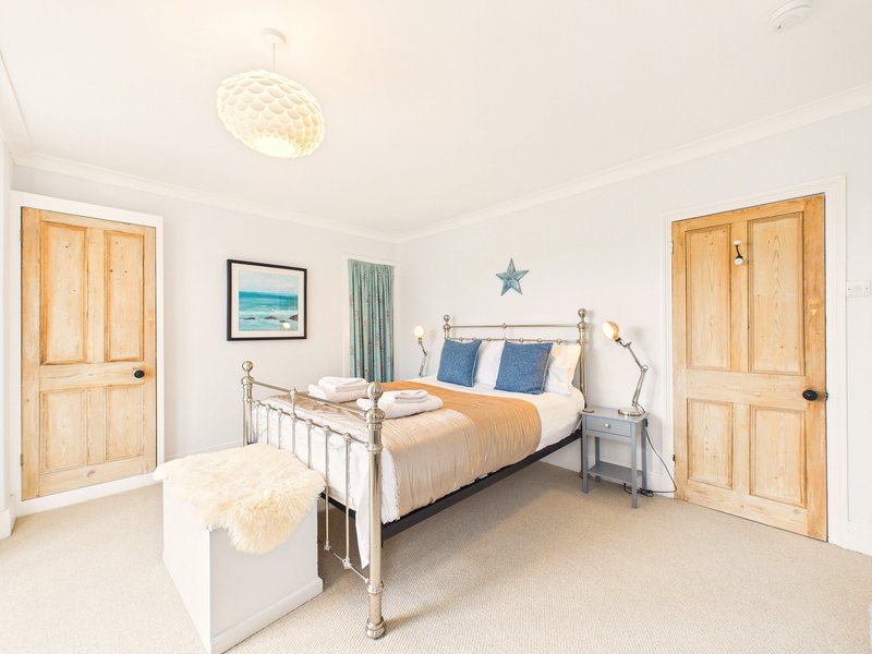 Bright bedroom with metal bed frame, blue pillows, wooden doors and pendant light