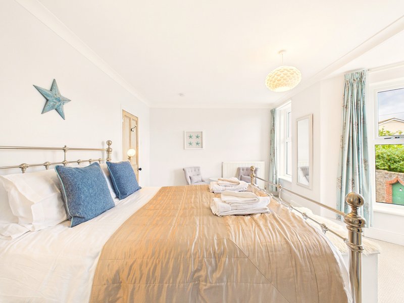 Bright bedroom with double bed, blue cushions, wooden furniture and garden views