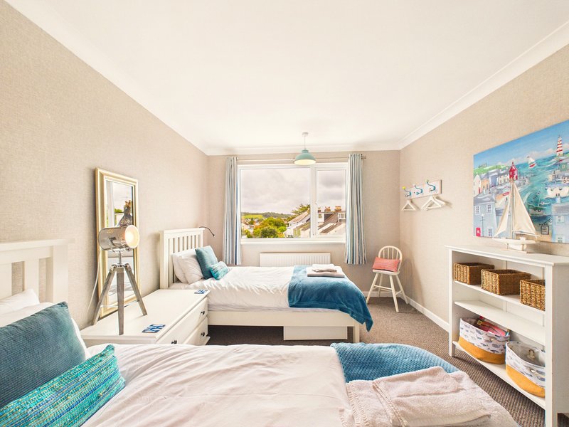 Bright bedroom with two single beds, white storage shelves, mirror, and coastal artwork on walls