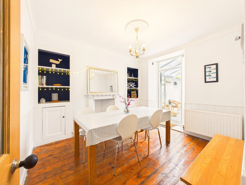 Bright dining room with wooden table, cream chairs, built-in shelving and gold pendant light