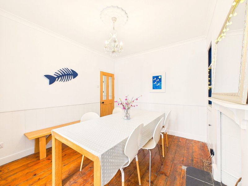 Bright dining room with wooden table, white chairs, chandelier, and wall art