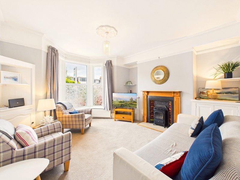 Bright living room with fireplace, comfortable seating, large windows and coastal decor