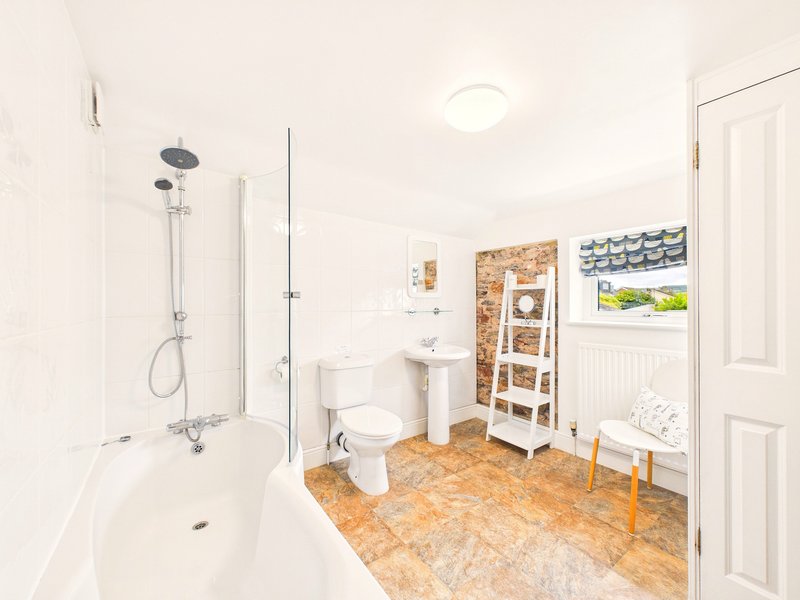 Bright bathroom with shower, toilet, pedestal sink, cork flooring and white walls