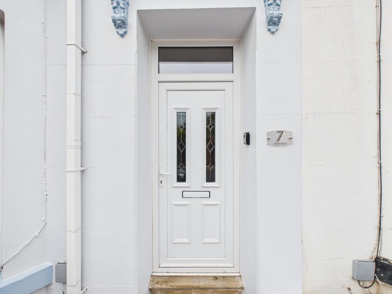 White front door with transom window and house number seven on white facade