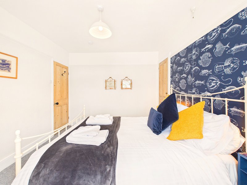Bright bedroom with double bed, yellow cushion, space-themed headboard and wooden doors