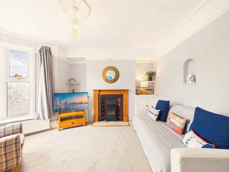 Bright living room with fireplace, blue sofa, yellow TV unit, and window with grey curtains