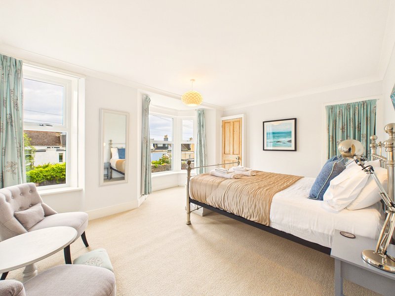 Bright bedroom with double bed, seating area, large windows overlooking garden