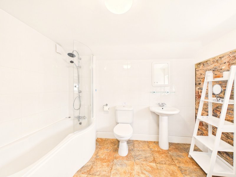 Bathroom with bathtub, toilet, pedestal sink, cork flooring and white ladder shelf