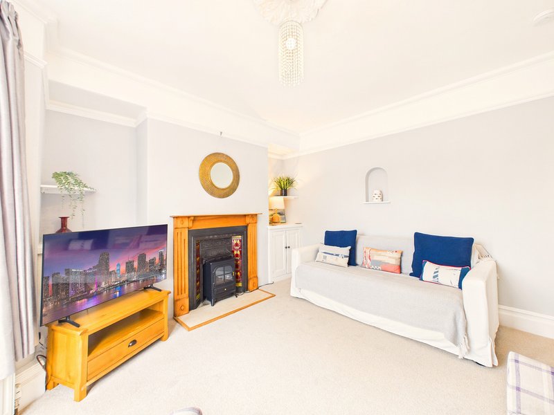 Bright living room with fireplace, white sofa with blue cushions, yellow TV stand and storage furniture