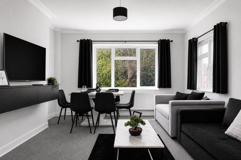 Modern living room with black and white furnishings, dining table, sofa, and garden views