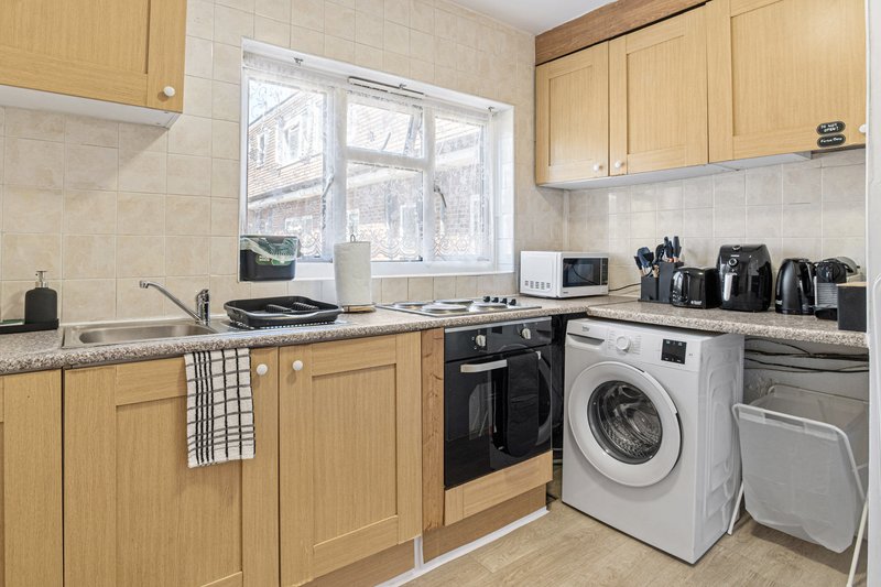 Kitchen with light wood cabinets, granite countertop, window, washing machine and appliances