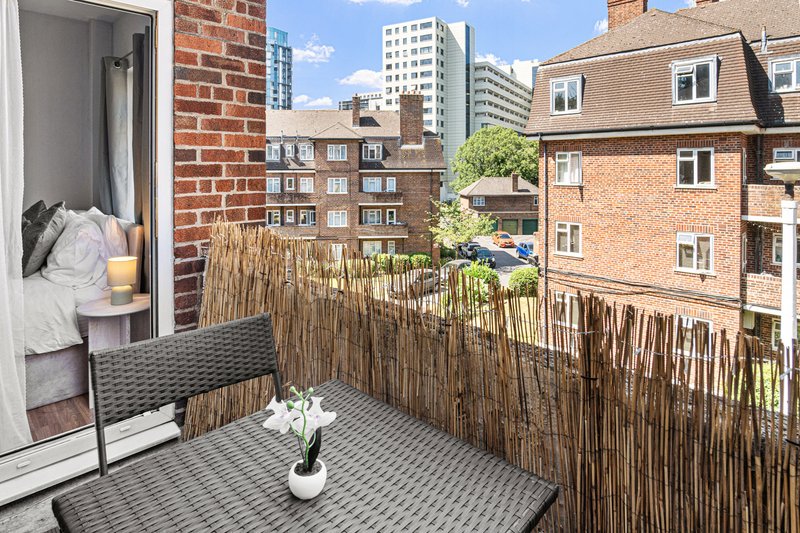 Balcony with wooden fence, potted plant, city skyline and surrounding residential buildings visible