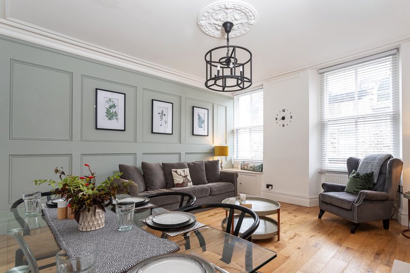 Bright living room with grey sofa, armchair, wooden floor and pendant ceiling light