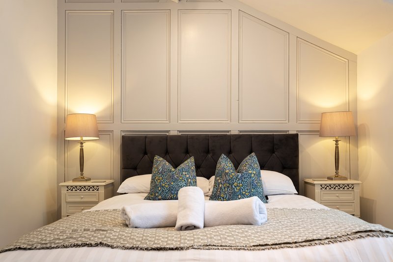Modern bedroom with black headboard, white bedding, decorative pillows, and bedside lamps