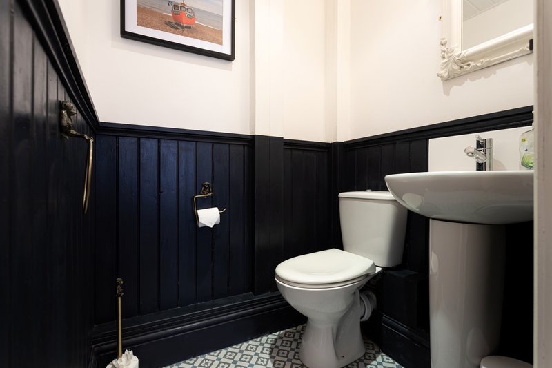 Modern bathroom with black panelled walls, white toilet, grey sink and patterned floor tiles