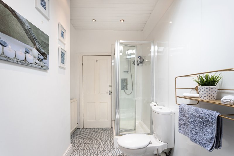 Modern bathroom with shower cubicle, toilet, sink and heated towel rail