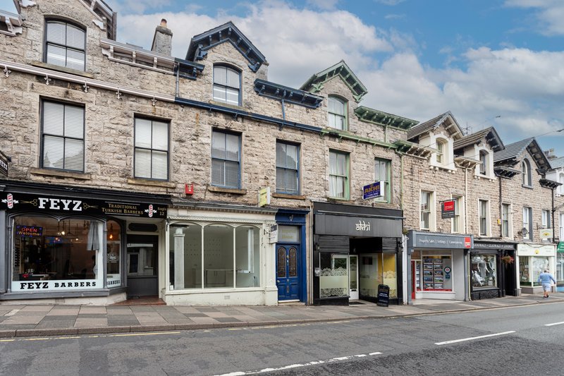 Street-view of stone terraced building with shopfronts and residential windows above