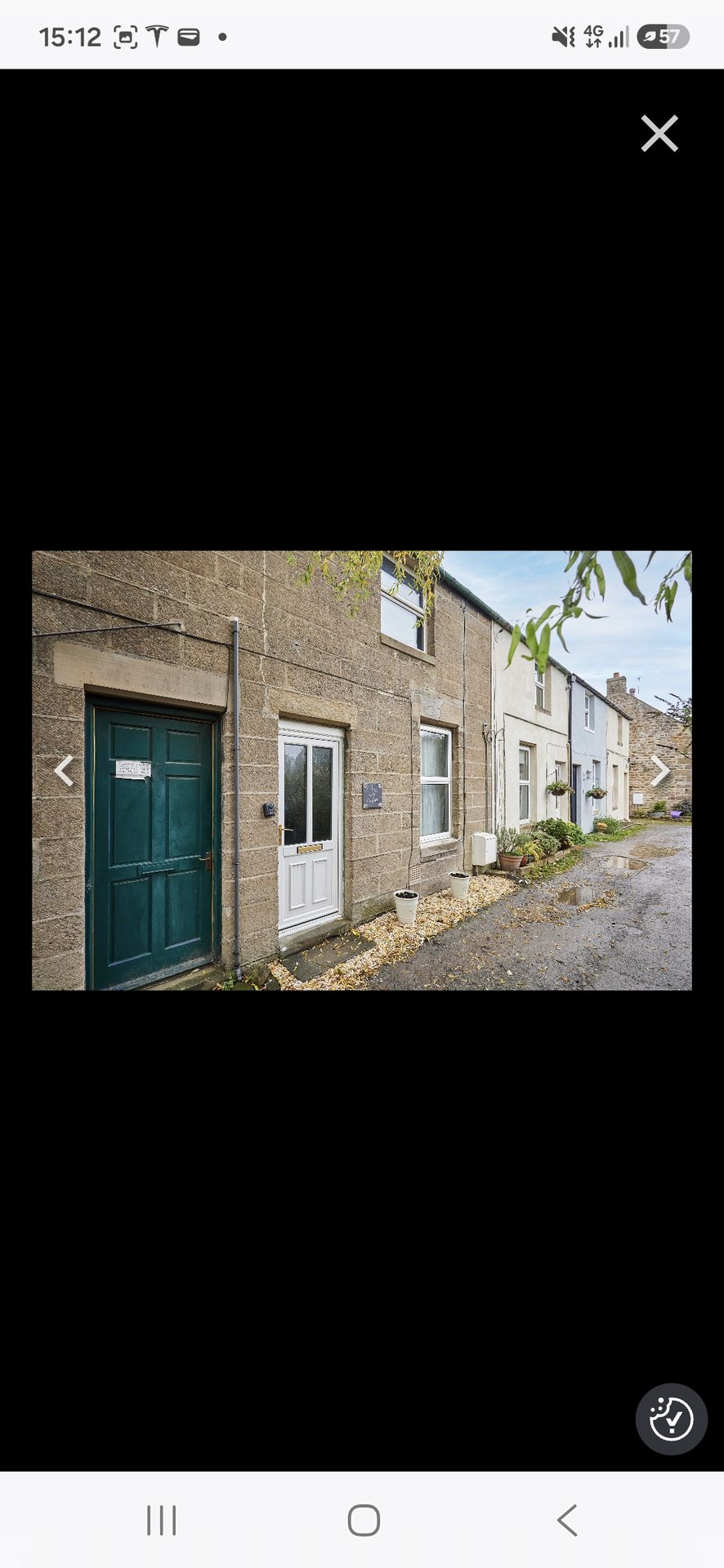 Row of brick terraced houses with green door, white door, and climbing ivy on facade