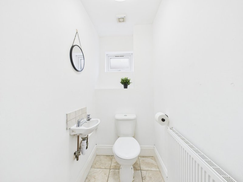 Small bathroom with toilet, wall-mounted sink, mirror and small potted plant