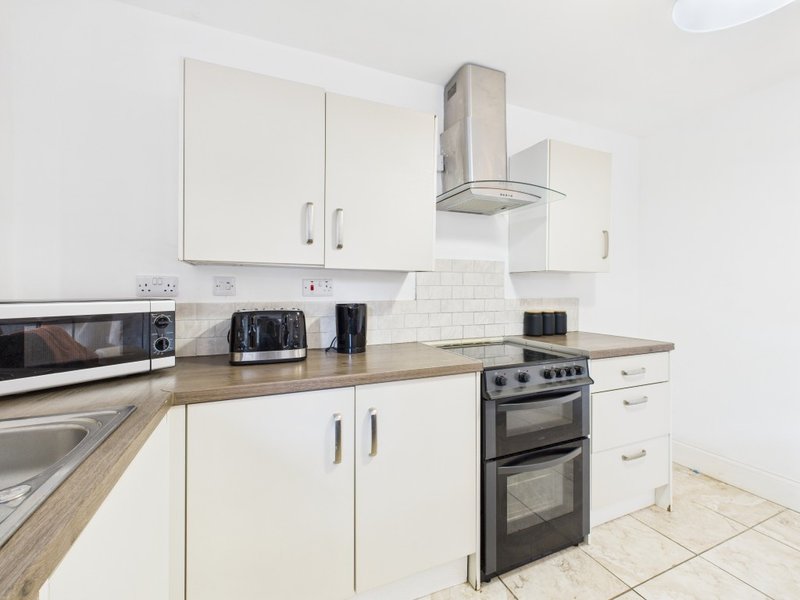 Modern kitchen with white cabinetry, wood countertop, stainless steel appliances and extractor hood