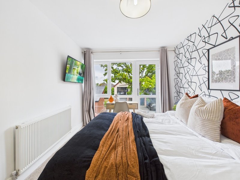 Bright bedroom with double bed, large window overlooking garden, and modern wall art