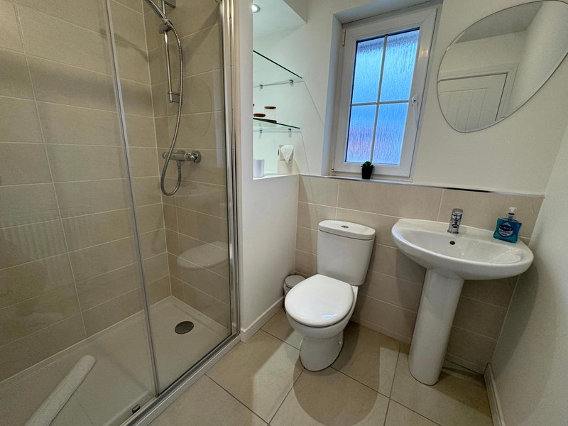 Modern bathroom with shower cubicle, toilet, pedestal sink and window